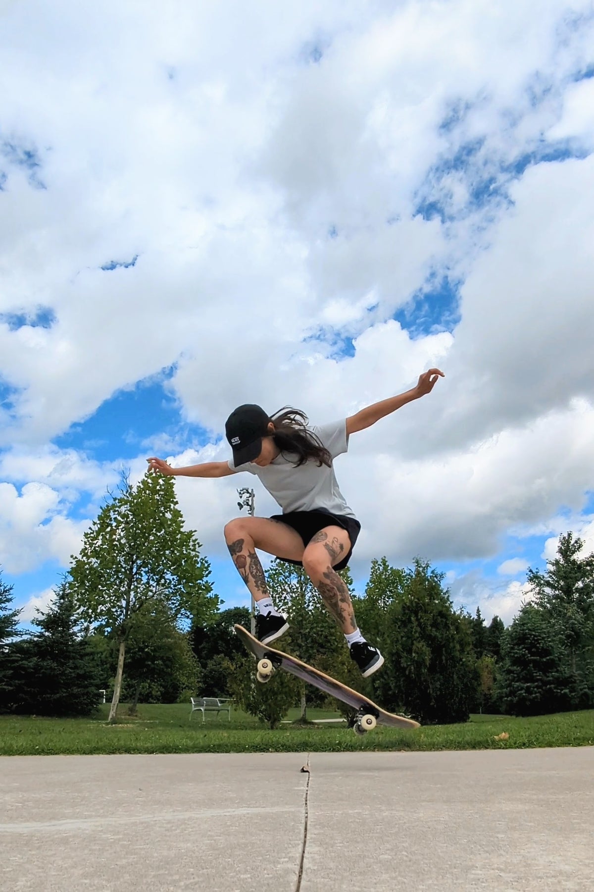 Person skateboarding, doing an ollie in mid-air against a blue sky with clouds