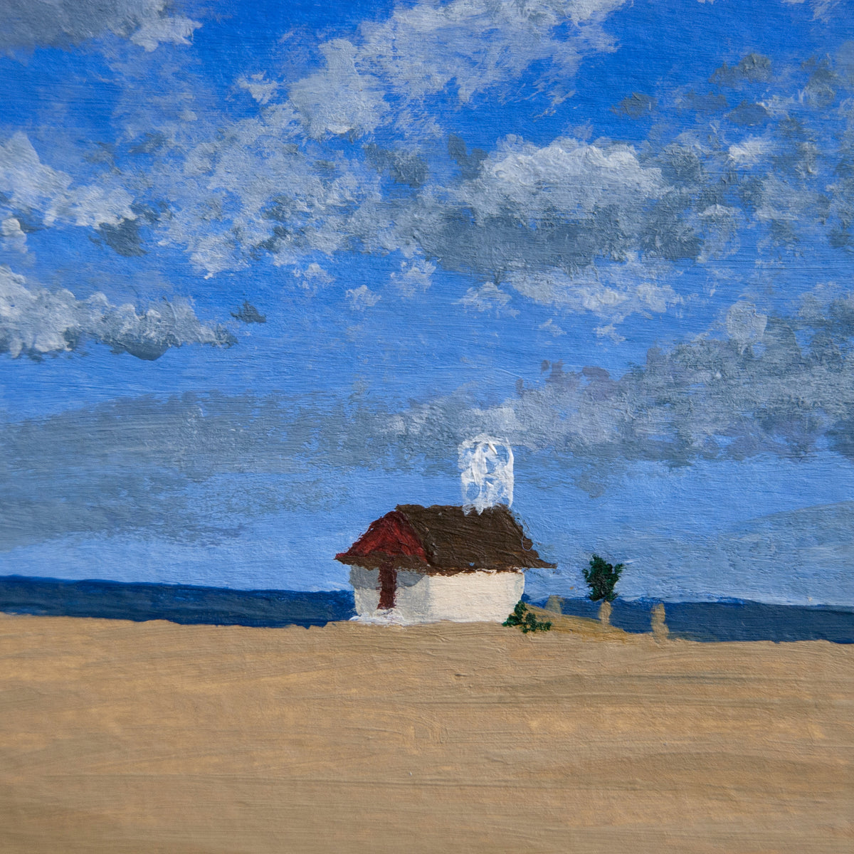 Small house with a red roof in a beach landscape under a blue sky with clouds.